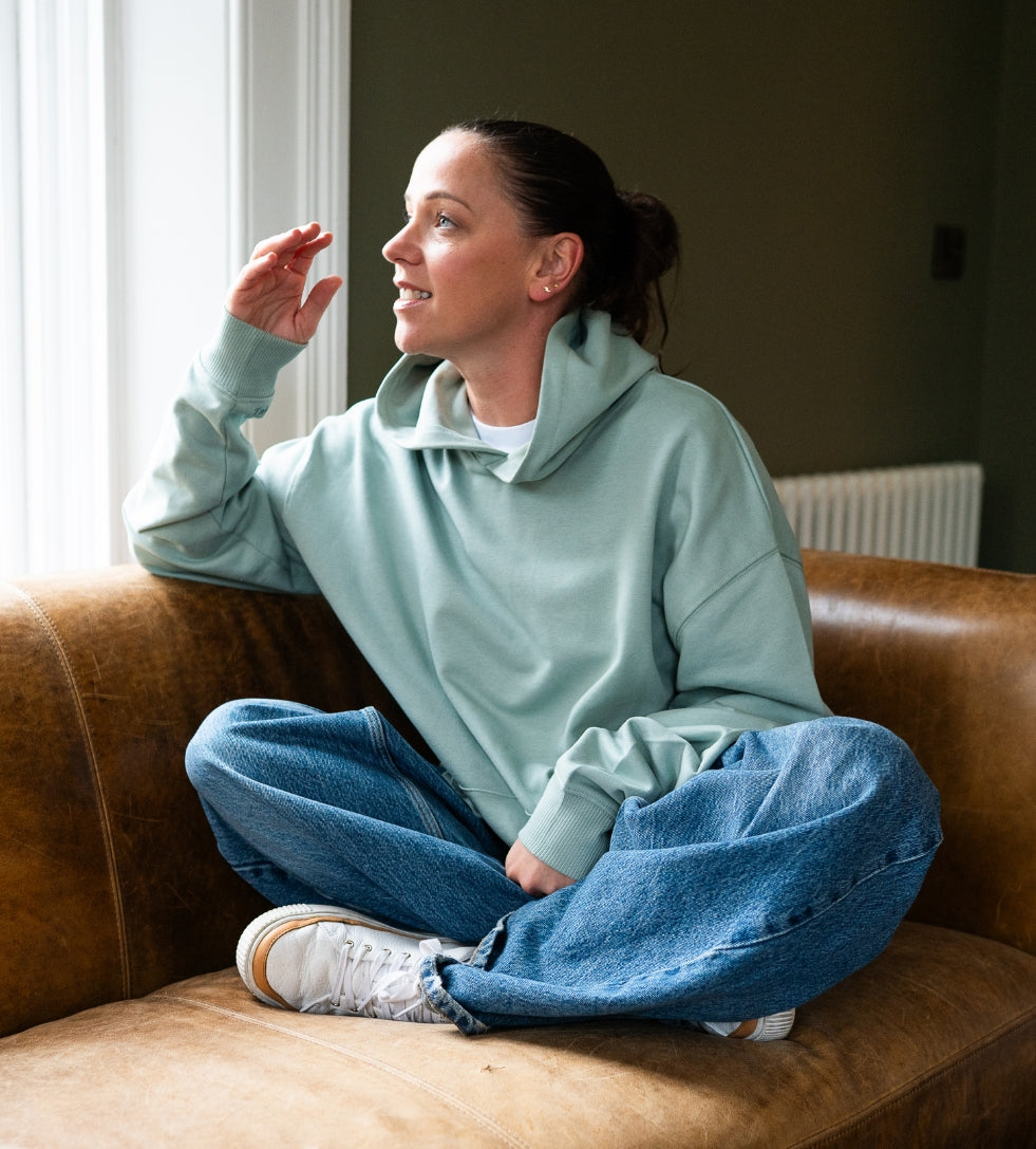 Girl sitting on a couch wearing Aloe hoodie by Every Little Thread