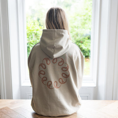 Girl sitting at window wearing Every Little Thread Hoodie in Sand Colour. Back View of logo